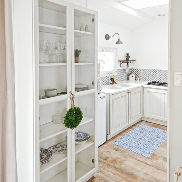 Cuisine de style campagne chic avec meubles blancs, sol en bois et vaisselier vitré